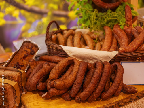 Different types of homemade smoked dry sausages hanging on a dark wooden background. Assortment of delicious deli meats, Salami and pepperoni
