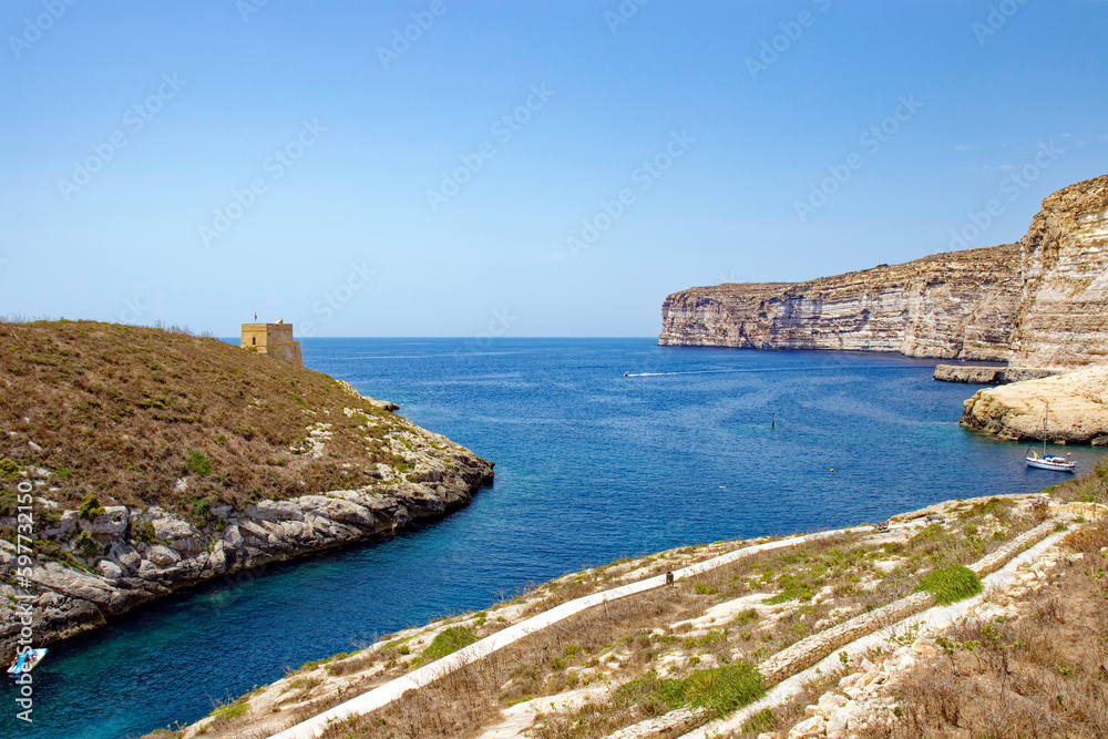 Scenic view of hill with stone tower and Mediterranean Sea at Island of Gozo on a sunny hot summer day. Photo taken August 10th, 2017, Gozo, Malta.