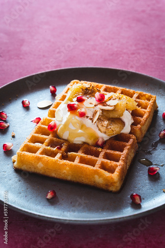 Waffel mit Joghurt Topping, karamellisierte Bananen, gerösteten Mandeln, Honig und Granatapfelkernen   