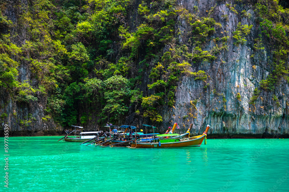 Many traditional longtail boats parking at Pileh Lagoon , Ko Phi Phi Leh island, part of Krabi, Thailand. View round with steep limestone hills and emerald green water.