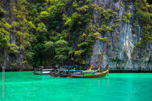 Many traditional longtail boats parking at Pileh Lagoon , Ko Phi Phi Leh island, part of Krabi, Thailand. View round with steep limestone hills and emerald green water.