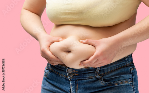 Close up of a obese young woman checking her fats with pink background
