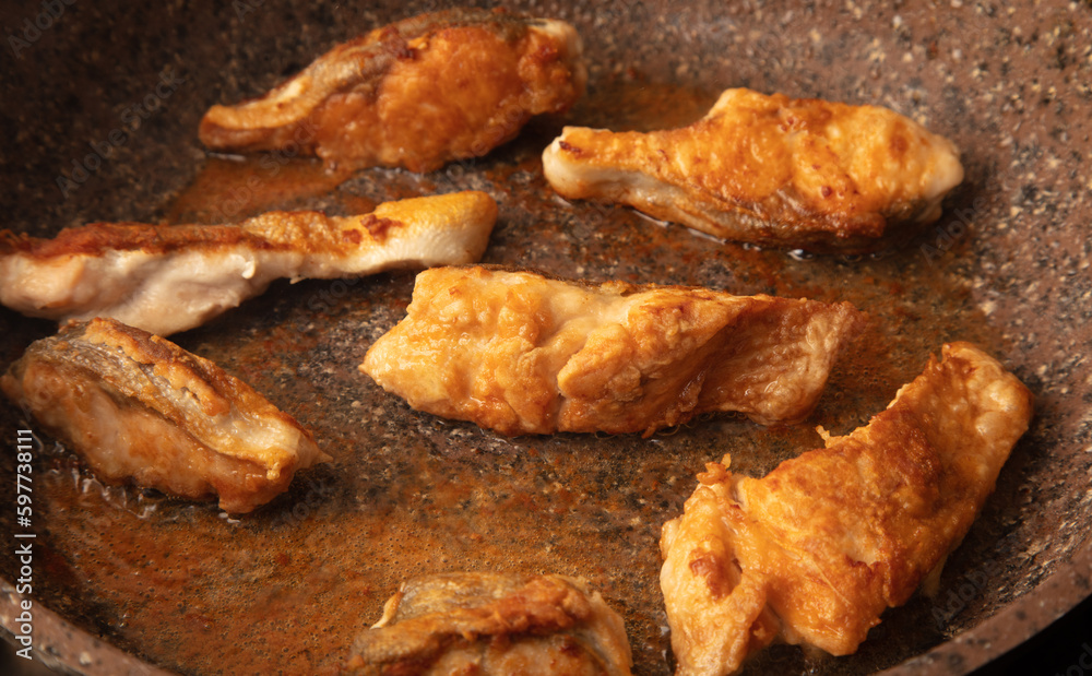 The fish is fried in a frying pan in oil. Close-up.