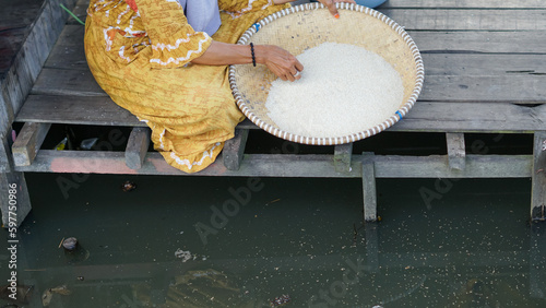 Banjar mothers in a rural village winnowing rice using a traditional basket called 