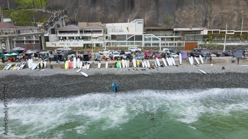 4K Aerial Drone Horizontal Tack along Rocky Beach with Surfers, Boards, and traffic in Lima, Peru