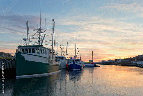 Fishing boats moored at the dock at sunset during the winter, Port de Grave, Newfoundland and Labrador, Canada.