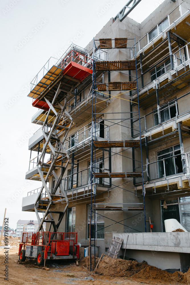 Hydraulic luffing jib tower cranes and workers being poured concrete into foundation. Cement pouring into formwork of building at construction site