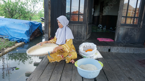 Banjar mothers in a rural village winnowing rice using a traditional basket called 