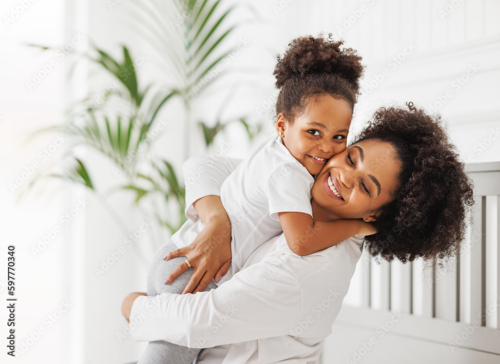 Obraz premium Happy ethnic family. African american mother and daughter play and laugh in bed
