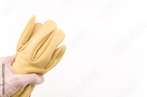 immagine primo piano con mano sinistra che impugna un paio di guanti da lavoro in pelle gialla, sfondo bianco photo