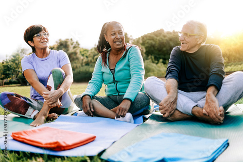Happy senior people after yoga sport class having fun sitting outdoors in park city - Elderly fitness concept