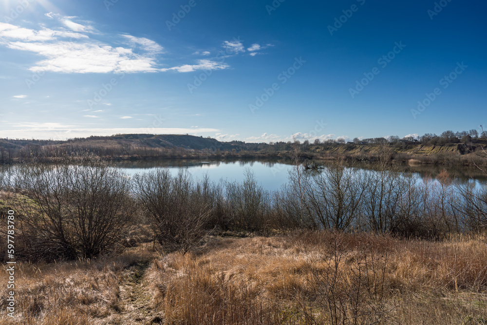 View over a landscape with small hills and lake created in a closed gravel pit in early spring Denmark