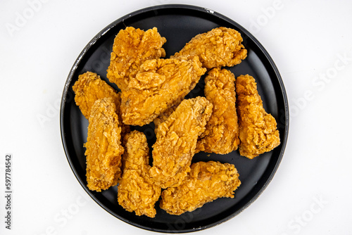 Fried chicken wings on a black plate isolated on white, top view