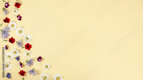 Floral composition, bright summer flowers on yellow in the form of a frame, top view, flat lay
