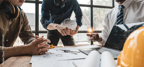 Civil engineer teams meeting working together wear worker helmets hardhat on construction site in modern city. Foreman industry project manager engineer teamwork. Asian industry professional team.