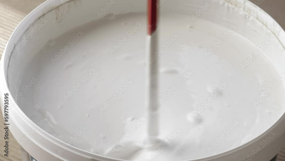 Mixing white paint in bucket, Closeup Mixing white paint in bucket, Closeup