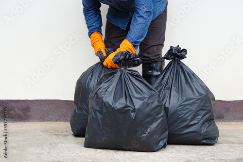 Closeup man holds black plastic bag that contains garbage inside. Concept , Waste management. Environment problems. Daily chores. Throw away rubbish .