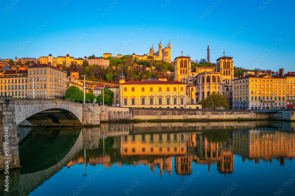 Lyon city skyline, buildings, and landmark architectures at sunrise with water reflections in the Saone River in France