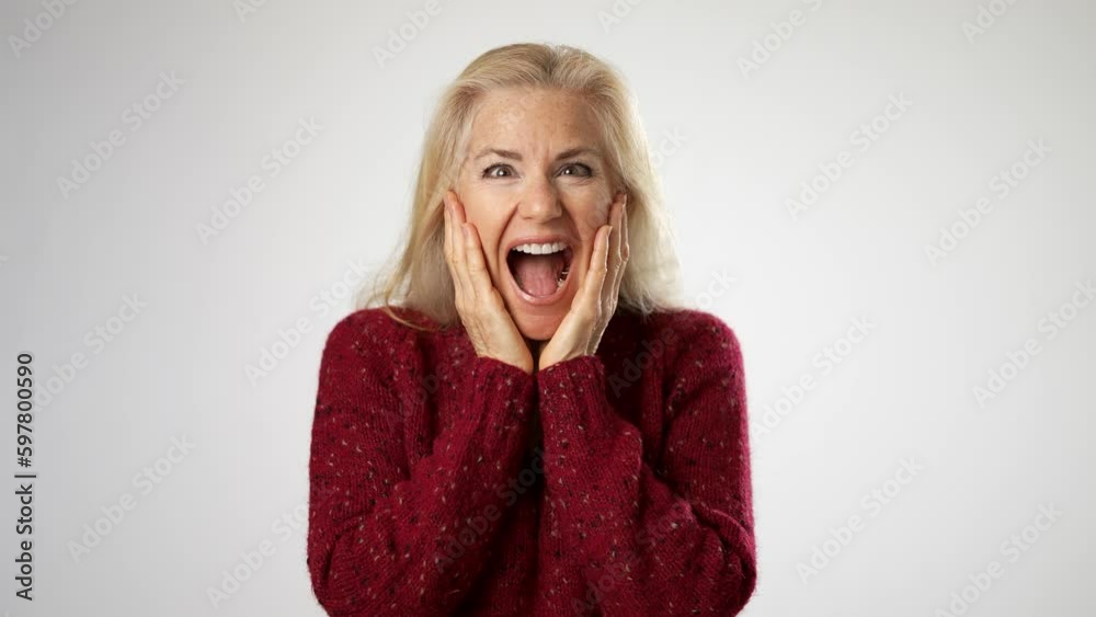 Excited shocked surprised elderly blonde woman lady 50s years old wear sweater shirt ask says wow omg no way say yes celebrating put hands on face isolated solid white background studio portrait