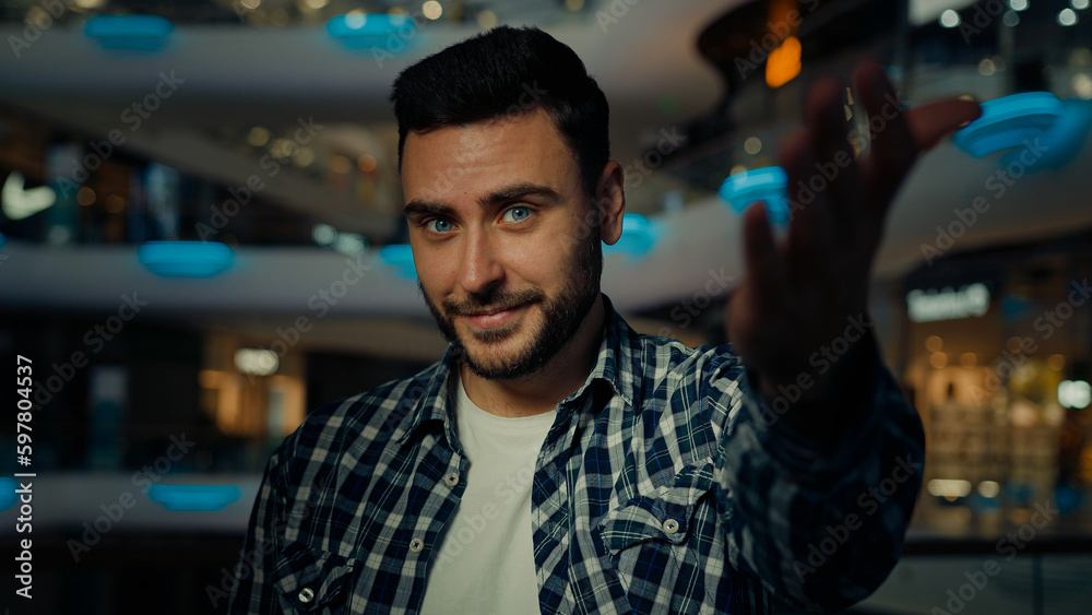 Fototapeta premium Happy positive young man motivated businessman make come here gesture beckoning invite to visit shopping center Arabian Hispanic friendly male freelancer expressing welcoming hospitality ask you join