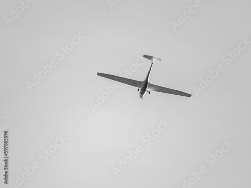 Glider with propeller flying in gray sky