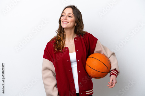 Young caucasian woman playing basketball isolated on white background posing with arms at hip and smiling