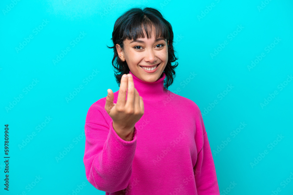 Young Argentinian woman isolated on blue background inviting to come with hand. Happy that you came Young Argentinian woman isolated on blue background inviting to come with hand. Happy that you came