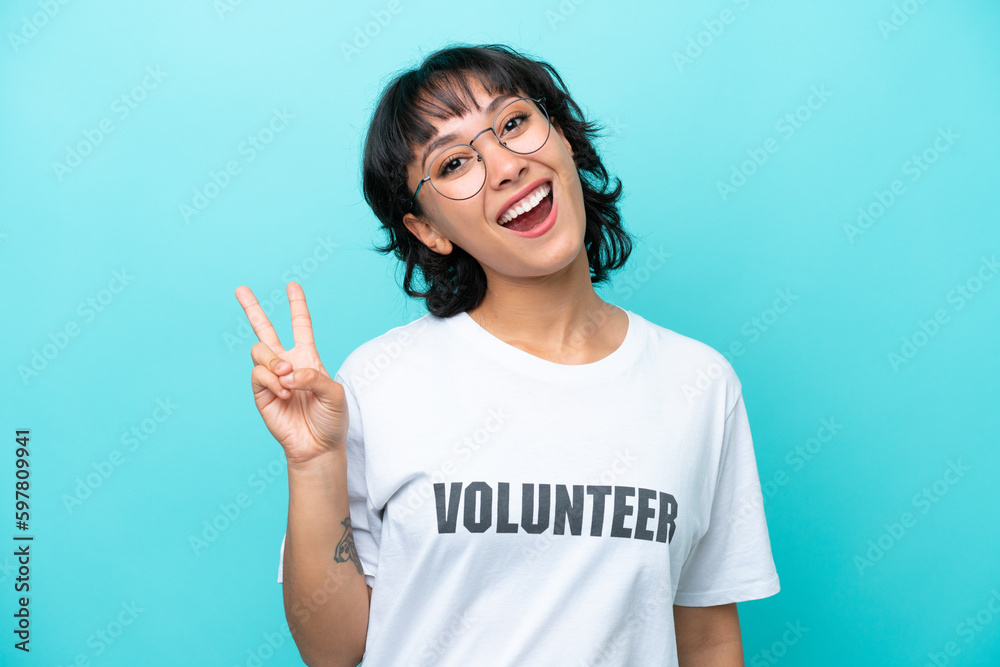 Young volunteer Argentinian woman isolated on blue background smiling and showing victory sign Young volunteer Argentinian woman isolated on blue background smiling and showing victory sign