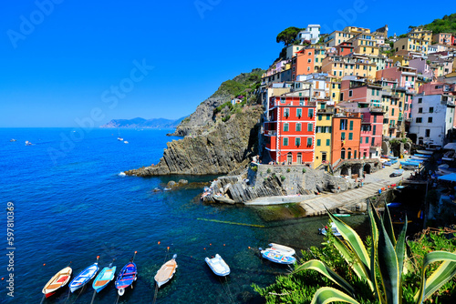 Colorful Cinque Terre village of Riomaggiore, Italy. View of the harbor with boats in the blue sea.