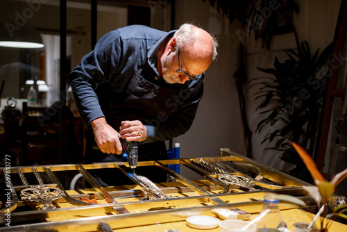 Man with tool screwing and repairing a bronze bed backrest