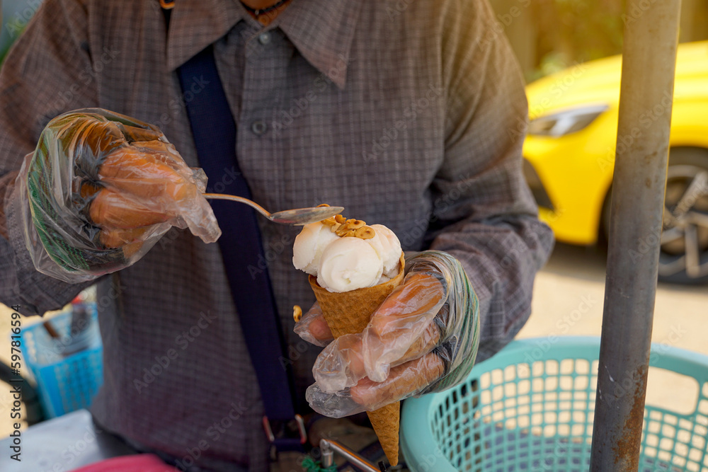 Street vendor selling homemade ice cream Sprinkling roasted peanuts on ice cream cones Coconut