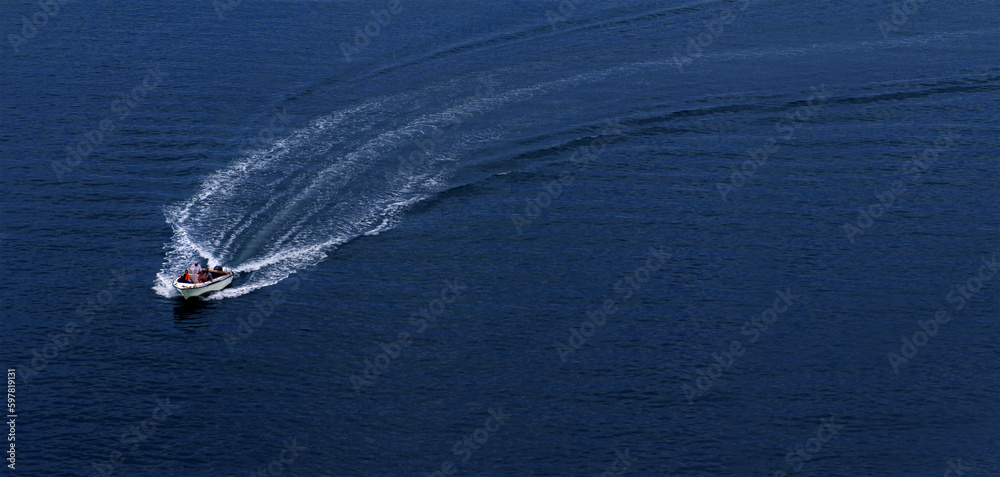 Naklejka premium A speedboat rushes at great speed through the water, leaving a foamy trail. View from above. Space for copying.