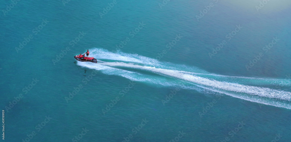 The jet ski rushes at great speed through the water, leaving a foamy trail in the sea. View from above. Space for copying. The jet ski rushes at great speed through the water, leaving a foamy trail in the sea. View from above. Space for copying.