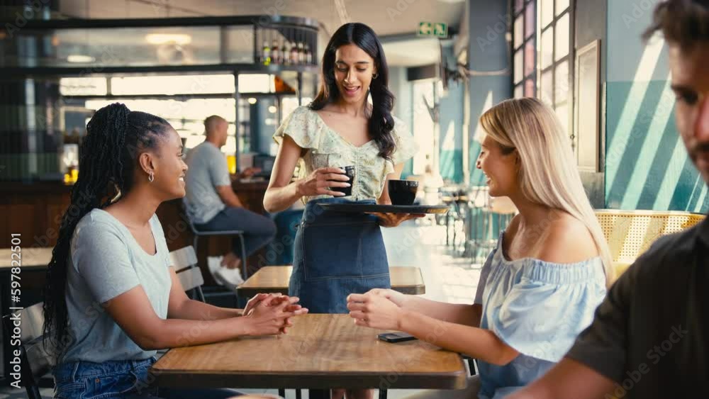Woman meeting friend in coffee shop paying bill with contactless mobile phone payment - shot in slow motion