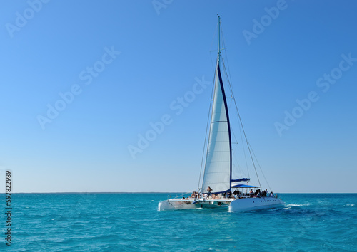 Catamaran with tourists on open sea, blue ocean and blue sky, copy space