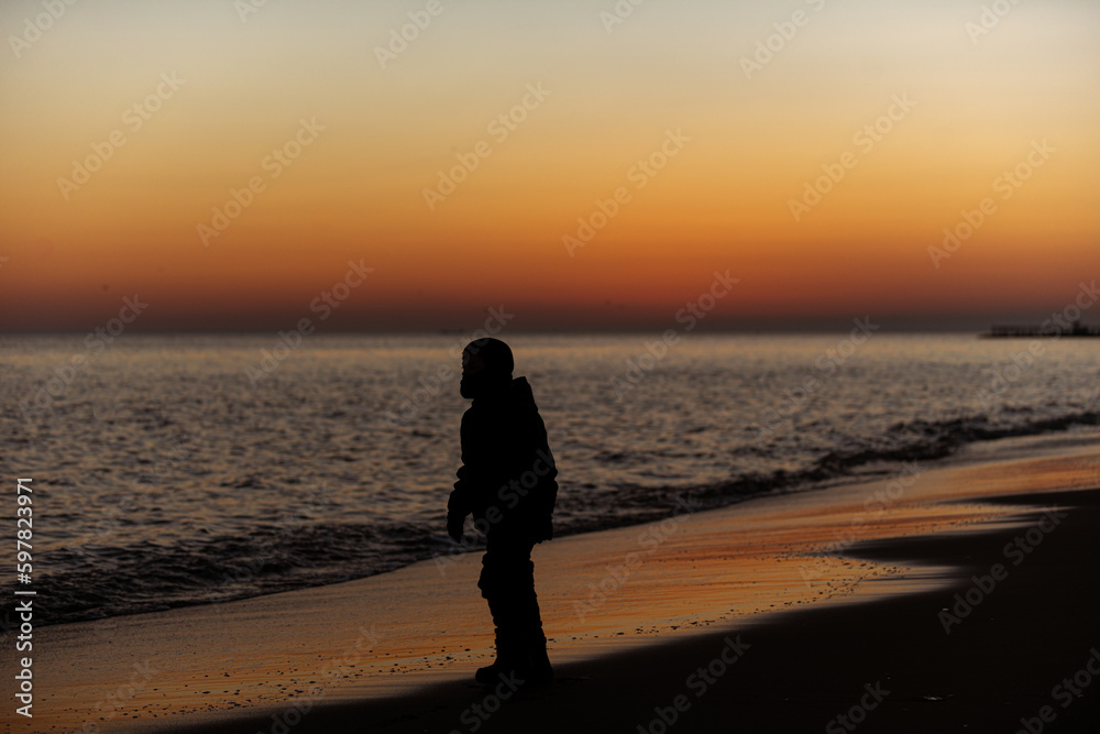 boy walking on the beach at sunset