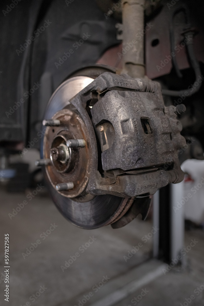 Brake pad on a car disc close-up. Car brake. Disassembled wheel. Disc without tire. Transport topic. Garage background. Replacing the brake box. Auto mechanic work.