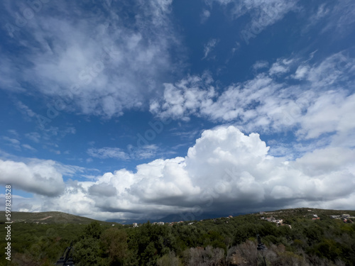 White cumulus clouds hang over a green meadow high in the mountains