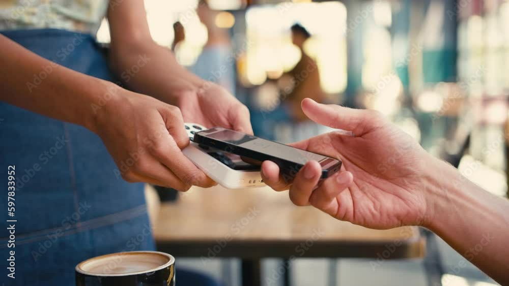 Close up of man in coffee shop paying bill with contactless mobile phone payment - shot in slow motion