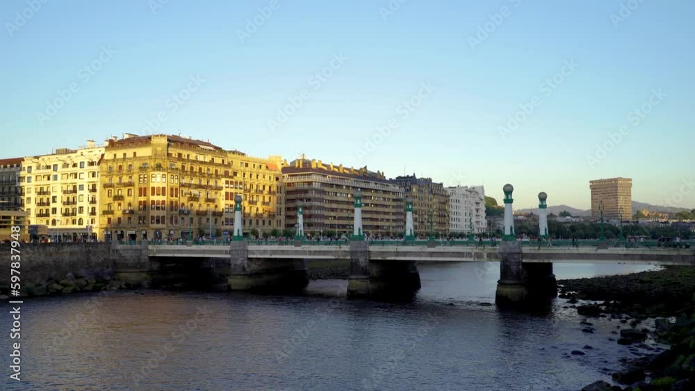San Sebastian, SPAIN - July 09 2022. View of Kursaal zubia Bridge, in the old city center of the town. Sunset colours. People and cars passing on the bridge. Stabilized static video. San Sebastian, SPAIN - July 09 2022. View of Kursaal zubia Bridge, in the old city center of the town. Sunset colours. People and cars passing on the bridge. Stabilized static video.
