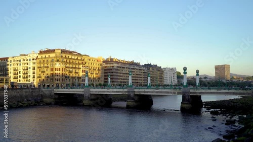 San Sebastian, SPAIN - July 09 2022. View of Kursaal zubia Bridge, in the old city center of the town. Sunset colours. People and cars passing on the bridge. Stabilized static video. photo