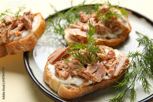 Plate with delicious tuna bruschettas on beige background, closeup