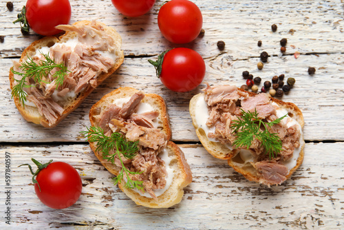 Delicious tuna bruschettas with tomatoes and peppercorn on white wooden table