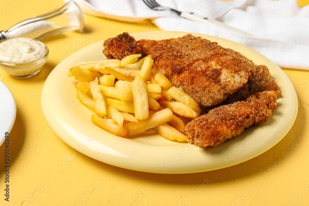 Plate of tasty fried codfish with french fries on yellow background Plate of tasty fried codfish with french fries on yellow background