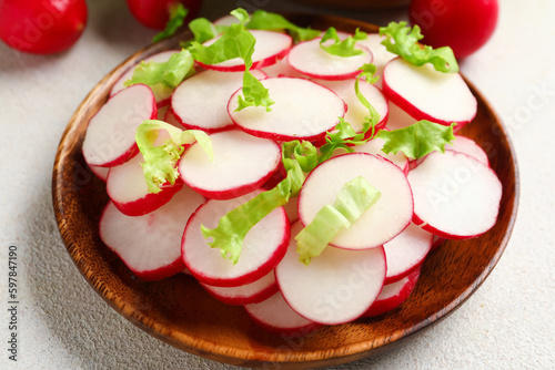 Bowl with fresh slices of radish and lettuce on white background