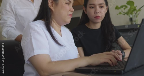 Asian women co-workers in workplace including person with blindness disability using laptop computer with screen reader program for visual impairment people. Disability inclusion at work concepts.