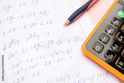 Copybook with maths formulas, pen and calculator, closeup