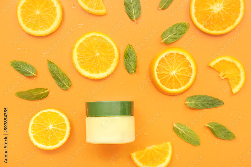 Jar of cosmetic cream with orange slices and mint on color background Jar of cosmetic cream with orange slices and mint on color background