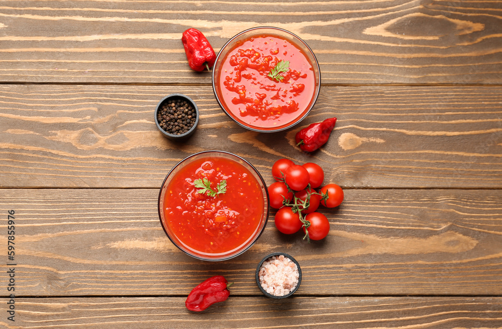 Bowls with tasty tomato sauce and fresh vegetables on wooden background Bowls with tasty tomato sauce and fresh vegetables on wooden background