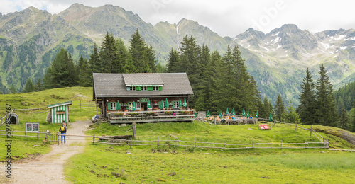 Vieuw on the Duisitzkarseehütte mountain hut in the Austrian Alps with a hiker in the foreground and beautiful pine trees and mountains in the background during summer.  12 juli 2020, Austria photo